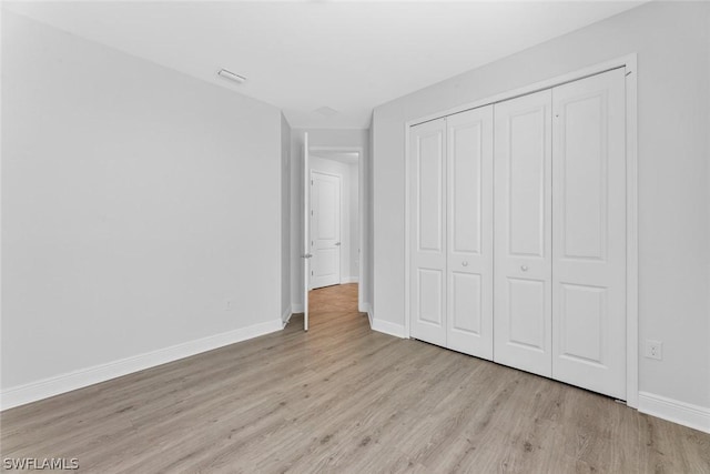 unfurnished bedroom with light wood-type flooring and a closet