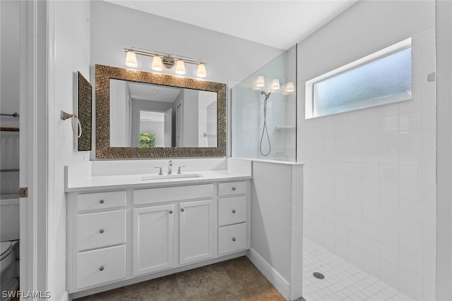 bathroom with vanity, toilet, and a tile shower