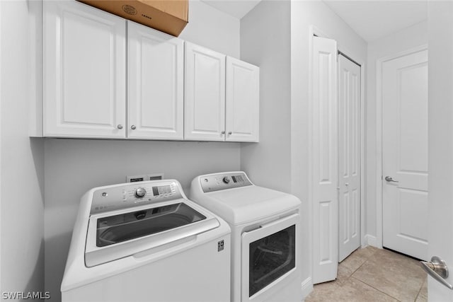 laundry room with cabinets, washer and clothes dryer, and light tile patterned floors