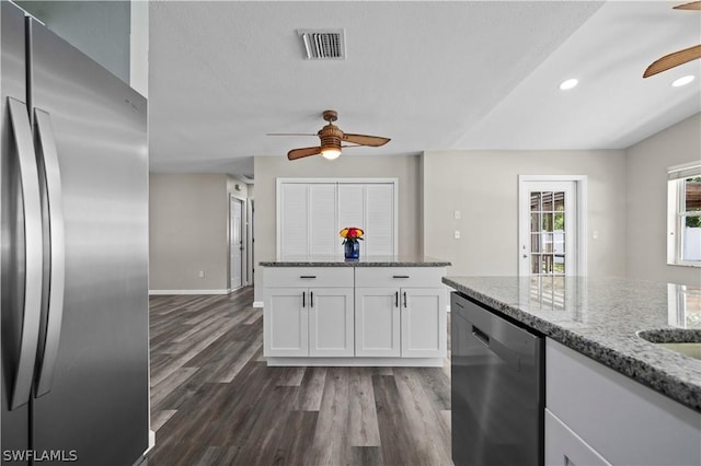 kitchen with dishwashing machine, dark wood-type flooring, visible vents, white cabinetry, and stainless steel refrigerator