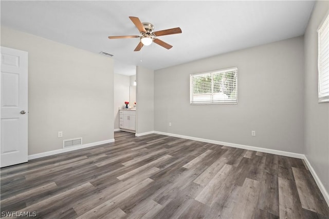 empty room featuring a ceiling fan, wood finished floors, visible vents, and baseboards