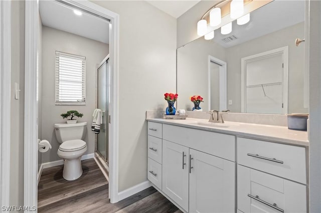 full bathroom with visible vents, toilet, wood finished floors, vanity, and a shower stall