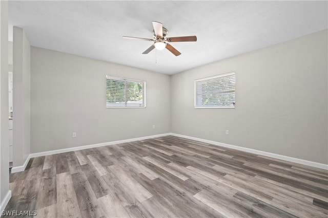 empty room with ceiling fan, baseboards, and wood finished floors