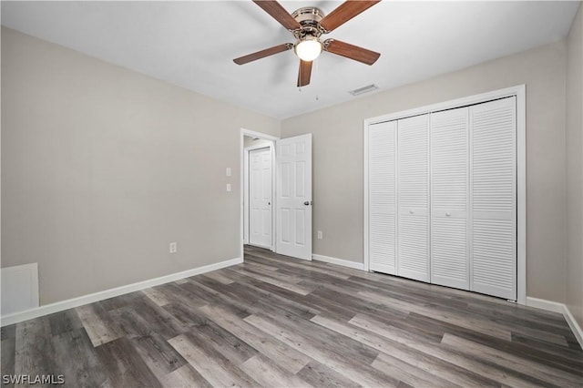 unfurnished bedroom with a closet, dark wood finished floors, visible vents, and baseboards