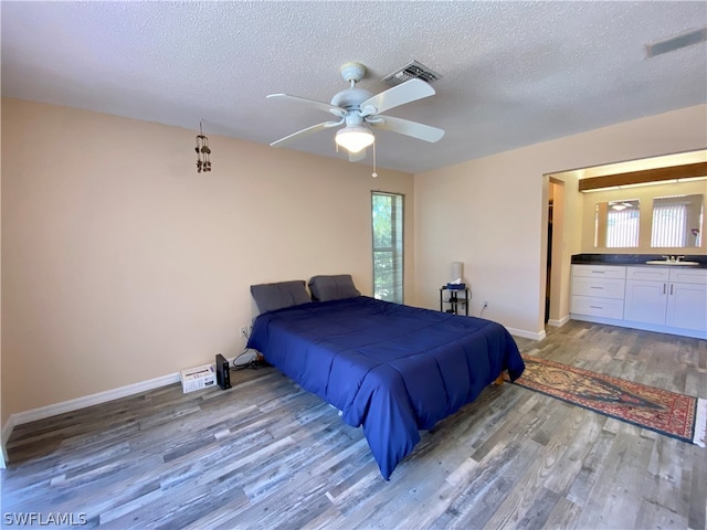 bedroom with sink, a textured ceiling, wood-type flooring, and ceiling fan