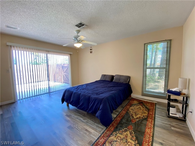 bedroom featuring ceiling fan, multiple windows, hardwood / wood-style floors, and access to outside