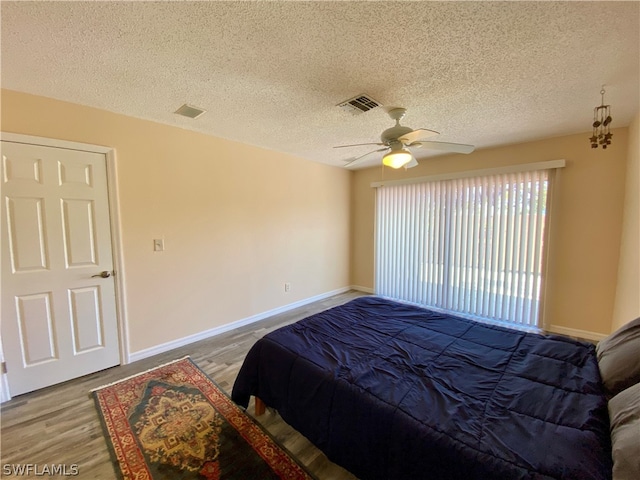 bedroom with a textured ceiling, ceiling fan, and hardwood / wood-style floors