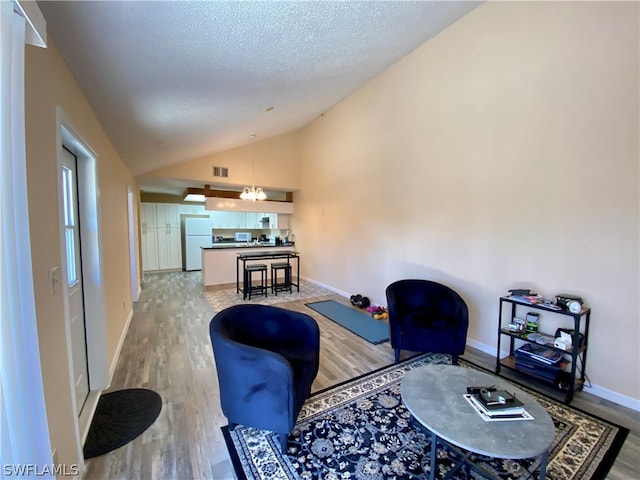 living room featuring a textured ceiling, vaulted ceiling, and hardwood / wood-style floors