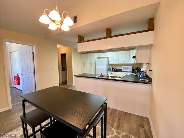 dining area featuring a notable chandelier, hardwood / wood-style floors, sink, and a textured ceiling