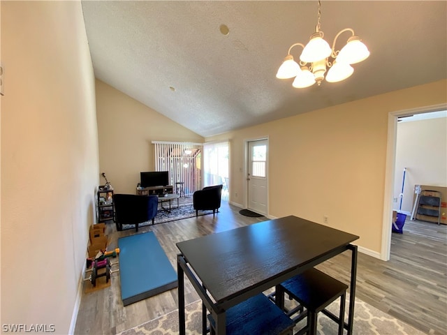 dining area featuring a notable chandelier, a textured ceiling, wood-type flooring, and vaulted ceiling