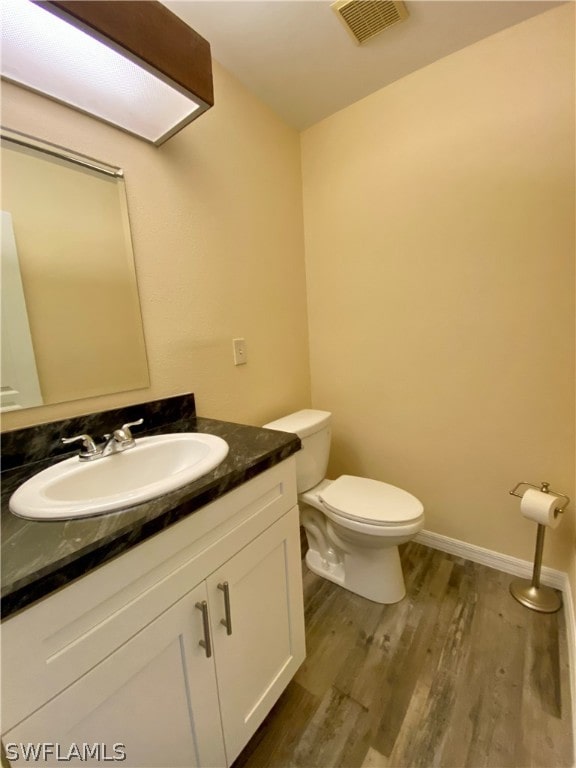 bathroom featuring hardwood / wood-style flooring, oversized vanity, and toilet