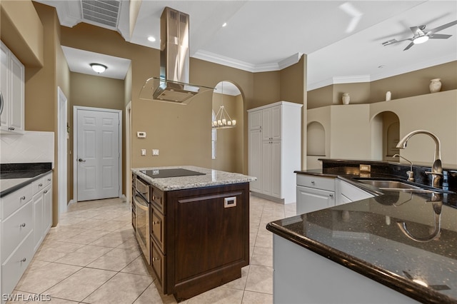 kitchen with sink, a kitchen island with sink, dark stone countertops, island range hood, and dark brown cabinets