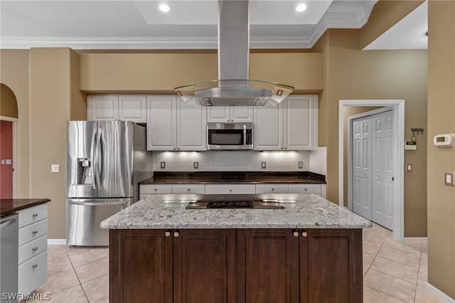 kitchen with island exhaust hood, appliances with stainless steel finishes, backsplash, and white cabinetry