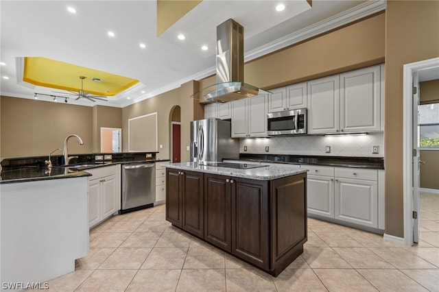 kitchen featuring a center island with sink, white cabinets, a raised ceiling, sink, and appliances with stainless steel finishes