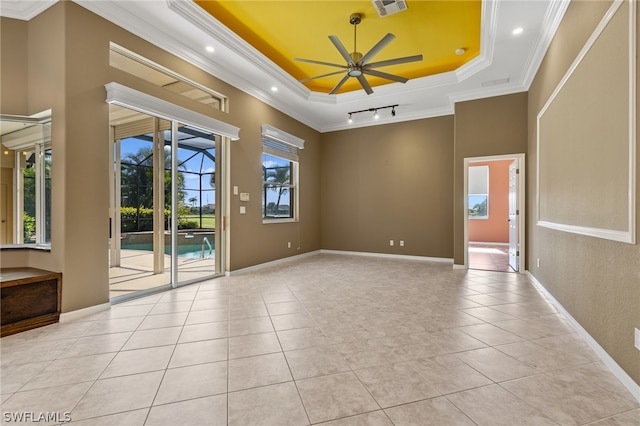 tiled empty room featuring a raised ceiling, ceiling fan, and crown molding