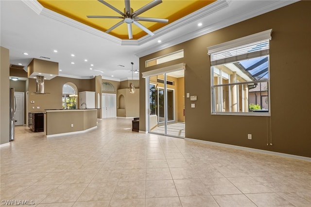 unfurnished living room featuring a tray ceiling, ceiling fan, crown molding, and light tile patterned floors