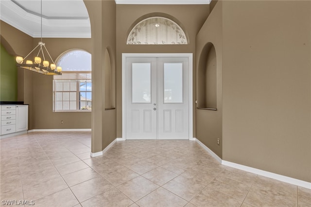 entryway featuring a raised ceiling, ornamental molding, light tile patterned floors, and an inviting chandelier