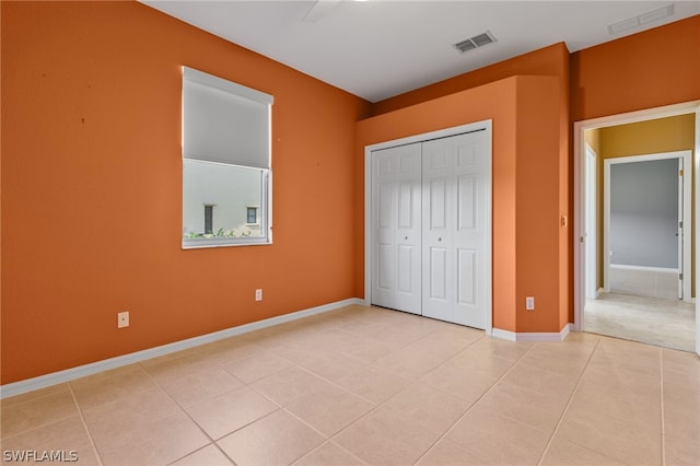 unfurnished bedroom with ceiling fan, a closet, and light tile patterned floors