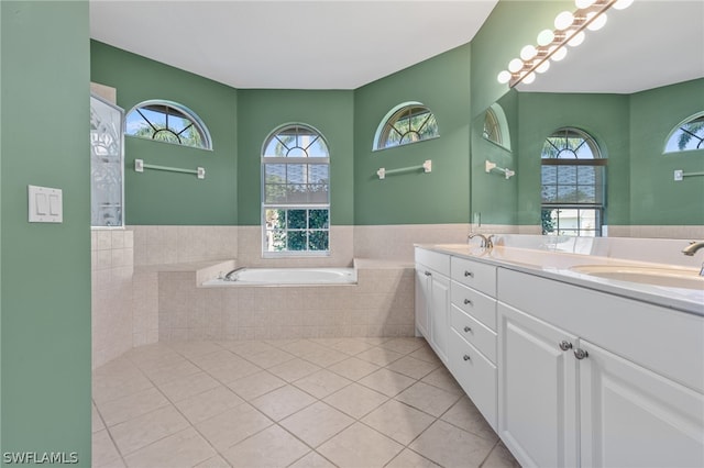 bathroom featuring tile patterned floors, vanity, a wealth of natural light, and tiled bath