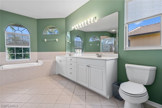 bathroom featuring tile patterned flooring, vanity, a healthy amount of sunlight, and tiled tub