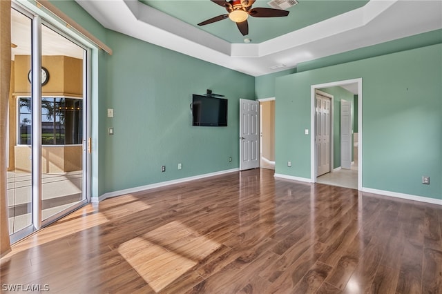 spare room featuring ceiling fan, a raised ceiling, and wood-type flooring