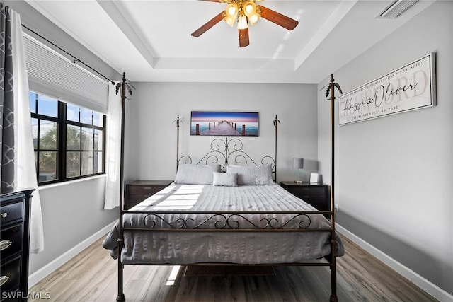 bedroom with a tray ceiling, ceiling fan, and hardwood / wood-style flooring