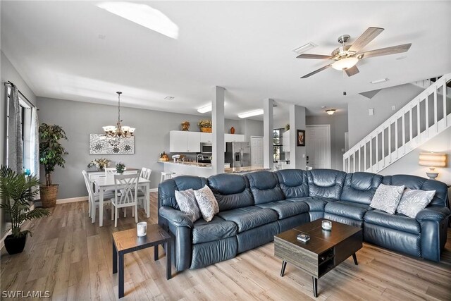 living room with light hardwood / wood-style flooring and ceiling fan with notable chandelier