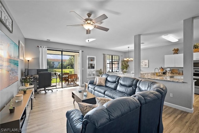 living room with sink, a healthy amount of sunlight, ceiling fan with notable chandelier, and light hardwood / wood-style floors