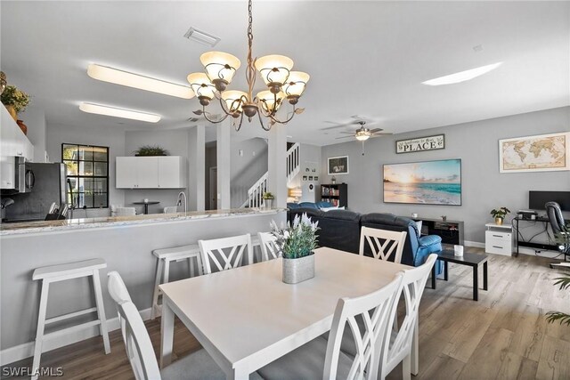 dining area featuring ceiling fan with notable chandelier and light wood-type flooring