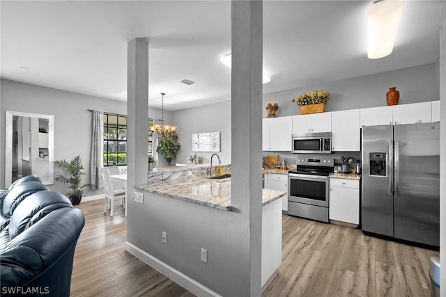 kitchen with white cabinetry, sink, stainless steel appliances, a chandelier, and decorative light fixtures