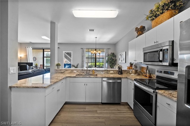 kitchen featuring sink, hanging light fixtures, kitchen peninsula, white cabinets, and appliances with stainless steel finishes
