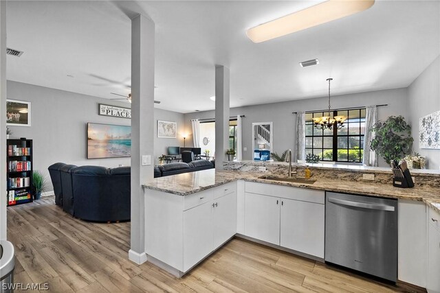 kitchen featuring light stone countertops, stainless steel dishwasher, sink, decorative light fixtures, and white cabinetry