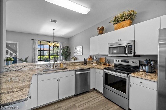kitchen with white cabinetry, sink, pendant lighting, a chandelier, and appliances with stainless steel finishes