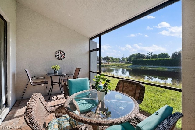 sunroom featuring a water view and vaulted ceiling