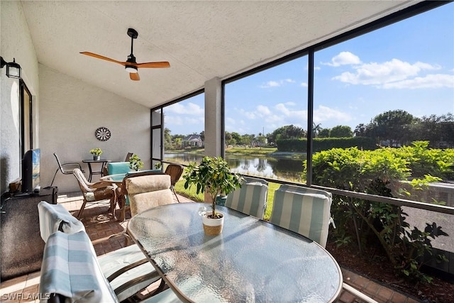 sunroom / solarium with ceiling fan, a water view, and lofted ceiling