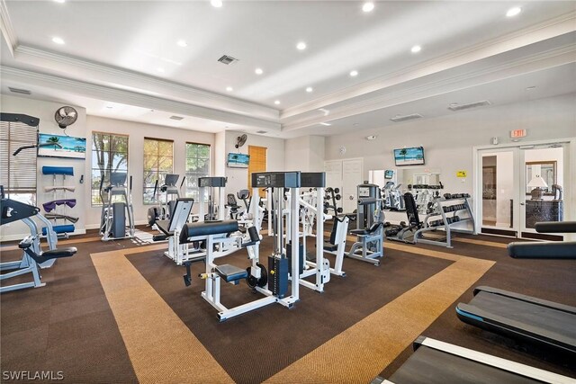 workout area with a raised ceiling, french doors, and ornamental molding