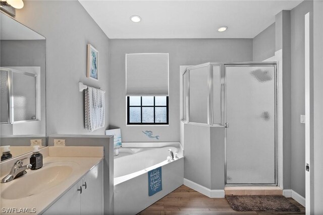 bathroom with plus walk in shower, vanity, and hardwood / wood-style flooring