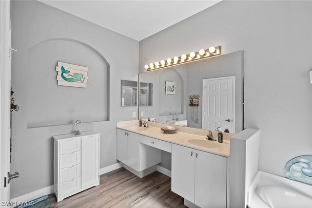 bathroom with a tub to relax in, hardwood / wood-style floors, and vanity