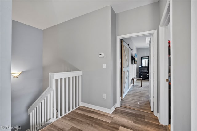 hallway featuring wood-type flooring and a barn door