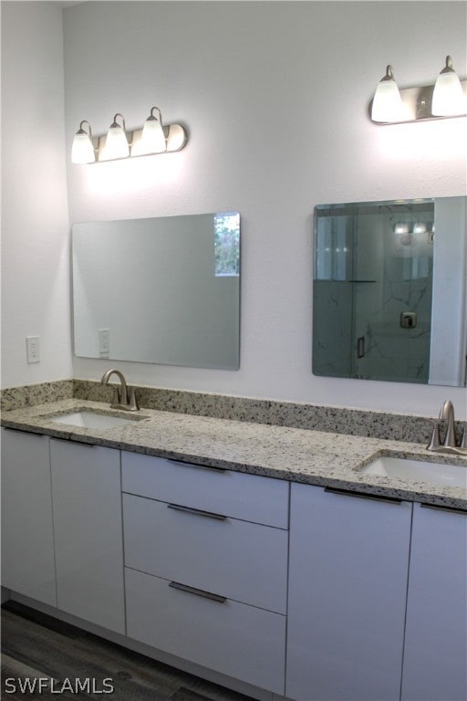 bathroom featuring double vanity, wood-type flooring, and a tile shower