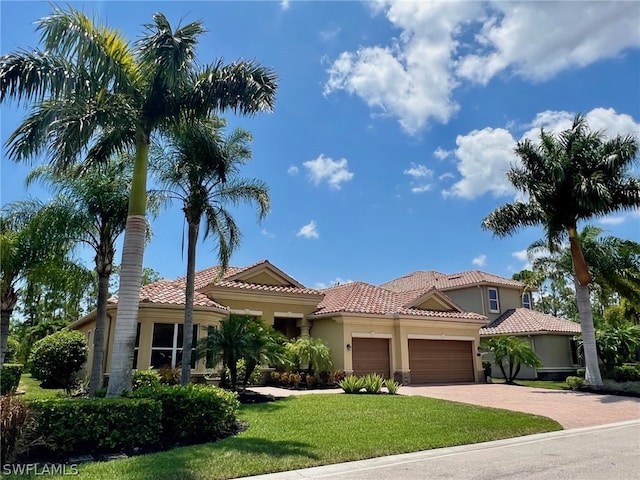 mediterranean / spanish home with a garage, driveway, stucco siding, and a tile roof