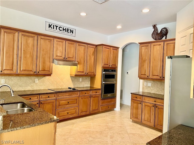 kitchen with backsplash, black electric stovetop, refrigerator, sink, and double oven