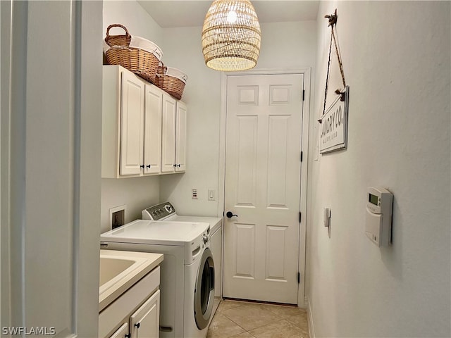 washroom with light tile patterned flooring, cabinets, and washing machine and clothes dryer