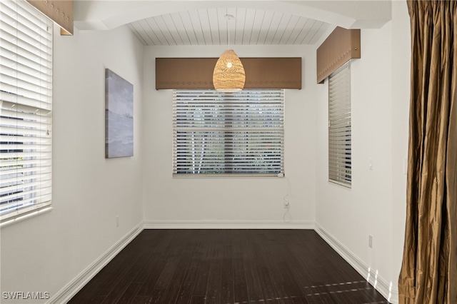 spare room with beam ceiling, wooden ceiling, and dark wood-type flooring