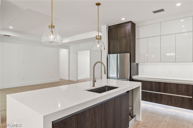 kitchen featuring stainless steel fridge, dark brown cabinetry, sink, decorative light fixtures, and white cabinetry