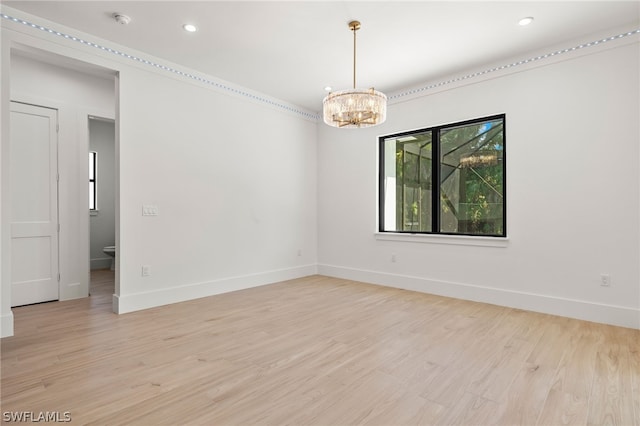 empty room featuring a chandelier and light hardwood / wood-style flooring