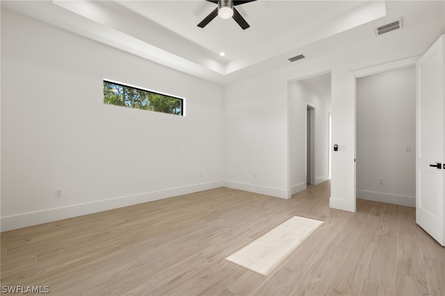 unfurnished bedroom featuring ceiling fan, light hardwood / wood-style floors, and a raised ceiling