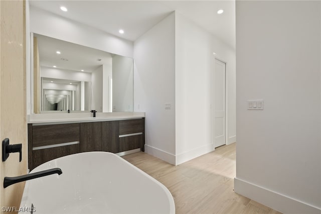 bathroom with wood-type flooring, vanity, and a tub