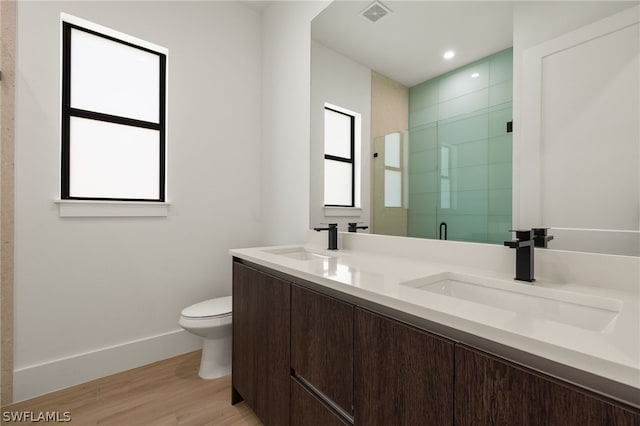 bathroom featuring hardwood / wood-style flooring, toilet, vanity, and walk in shower