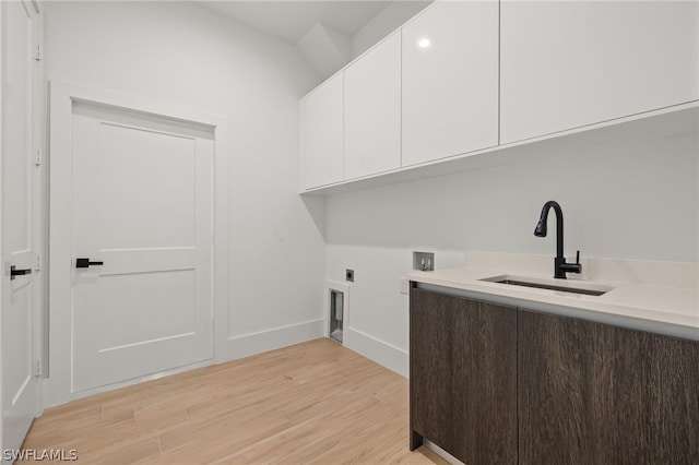 laundry room with cabinets, hookup for a washing machine, light wood-type flooring, hookup for an electric dryer, and sink